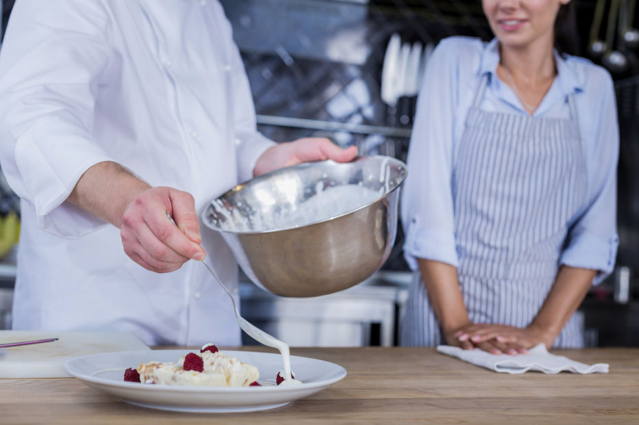 Sweet cream. Confident experienced chef adding some cream to a dessert while cooking it